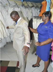 JNSBL client Karlene Campbell-Blair (right) adjusts a suit on a customer at her bridal store, Angels Bridal in May Pen, Clarendon. Campbell-Blair runs a bridal store, a flower shop and a clothes shop in the May Pen Market.